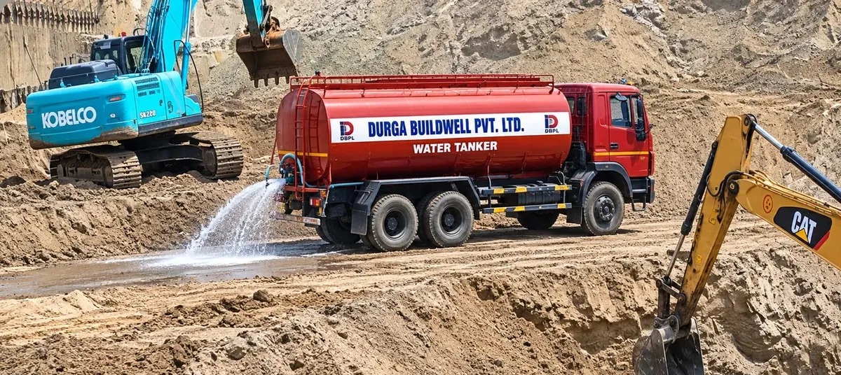 Durga Buildwell water tanker sprinkling a haul road beside excavators in a basement pit
